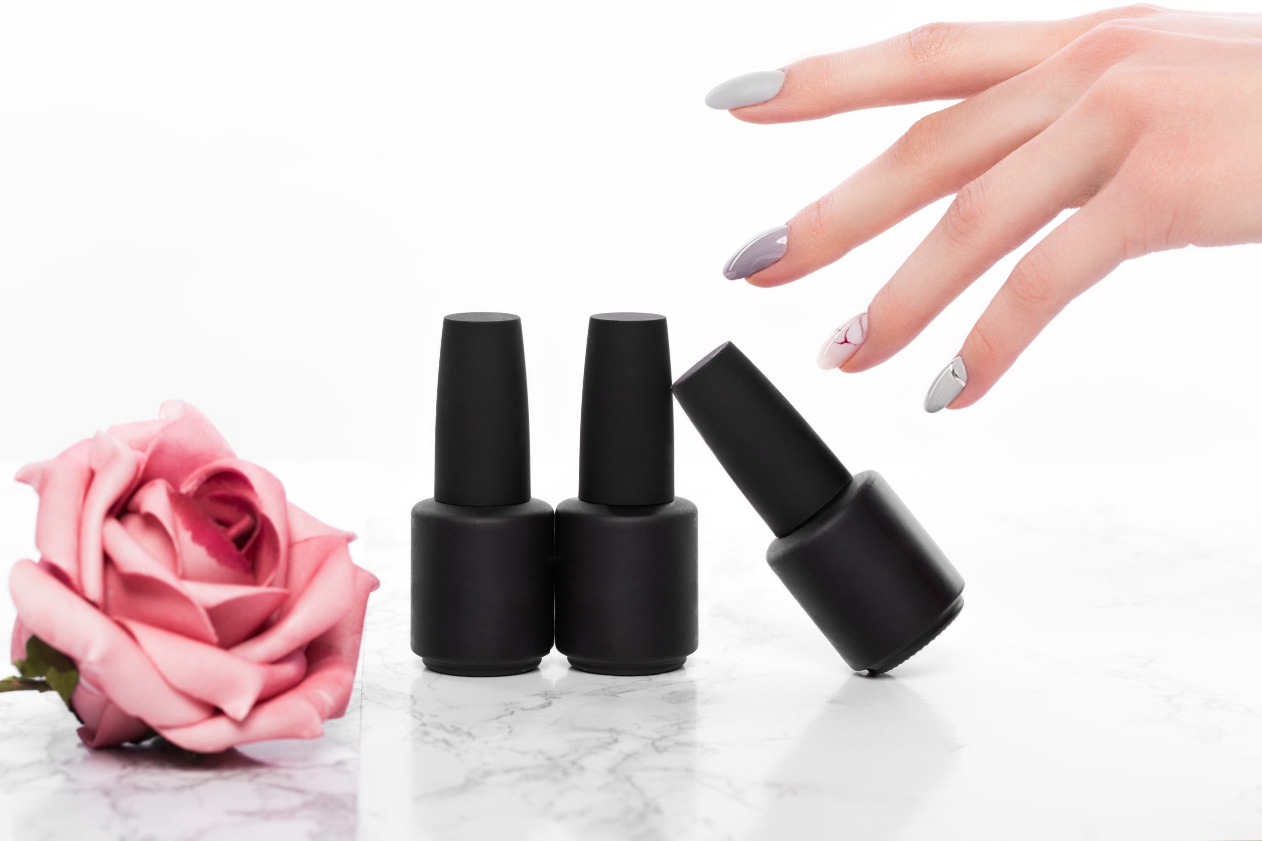 Black bottles of nail glue on a background of flowers. Manicure design. nail polish. nail lacquers. nail adhesive.