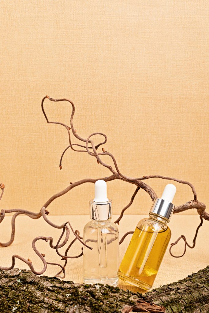 Clear and amber serums in glass bottles with wooden nature elements on sand beige background. Natural eco friendly beauty products concept. Closeup. Cuticle oils. nail care. hand care