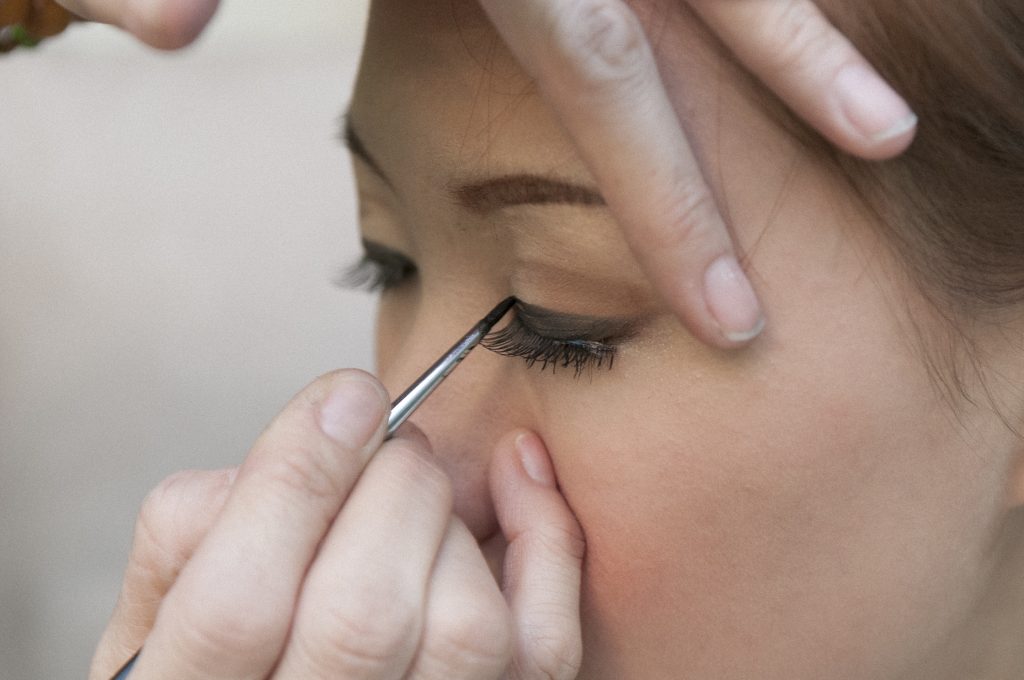 Closeup of hand applying eyeliner during makeup. A Simple Step-by-Step Process to Perfect Liner