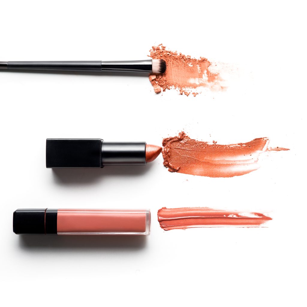 Creative concept photo of cosmetics swatches on white background. Liquid vs. Bullet lipsticks.