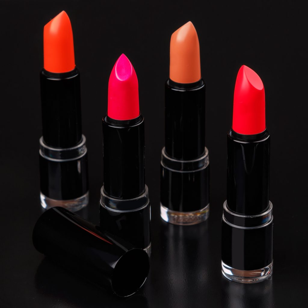 Different lipsticks on black background.