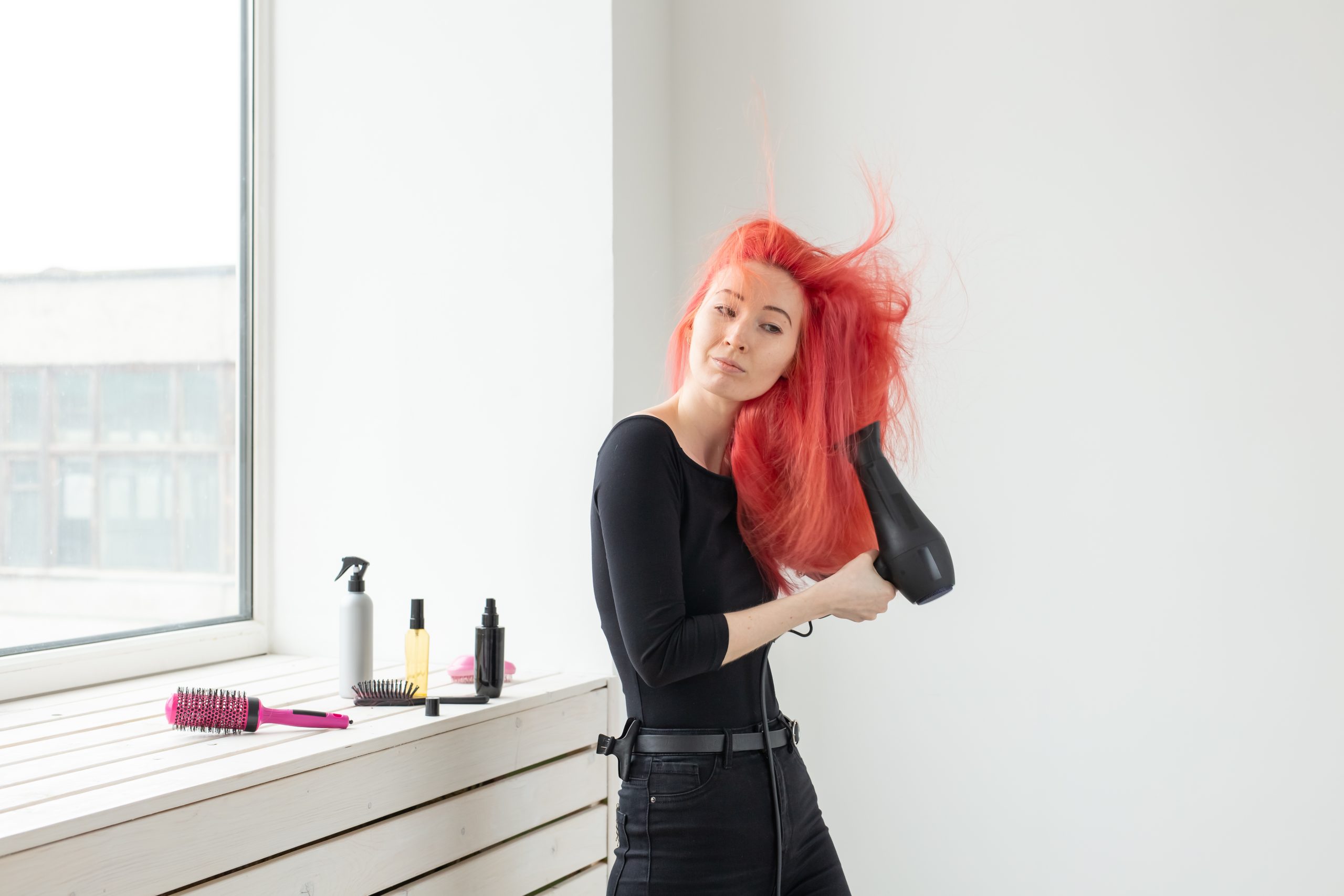 Hair Color Last Longer. Hairdresser, beauty salon and people concept - young woman hair stylist with hair dryer on white background. Minimizing Heat Styling to Prevent Fading
