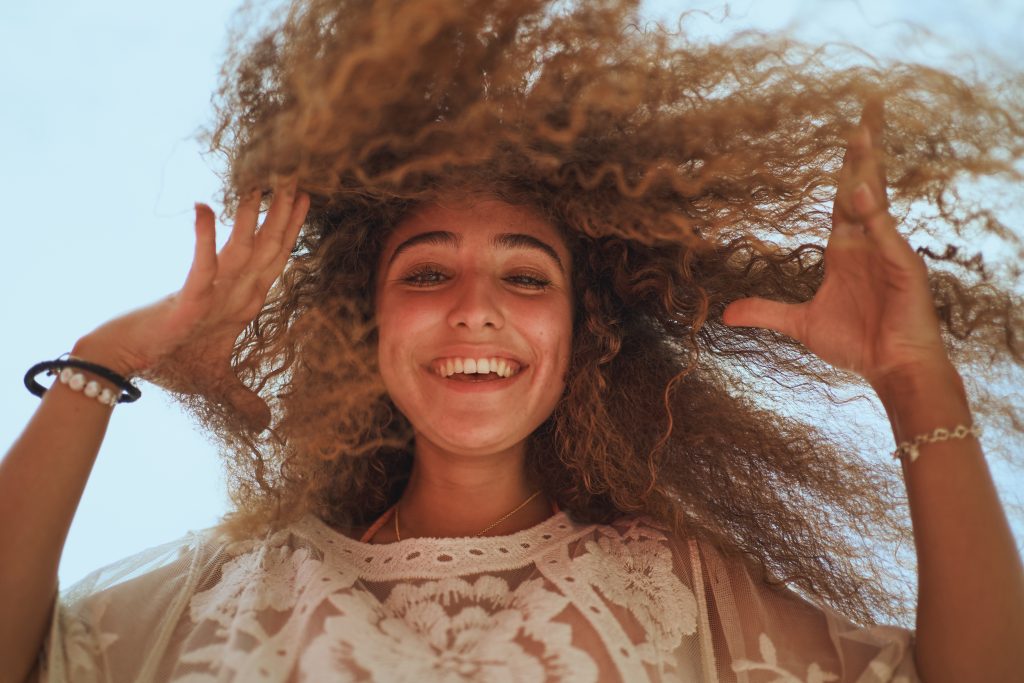Low angle portrait of cheerful woman with stylish hair smiling to cameraز