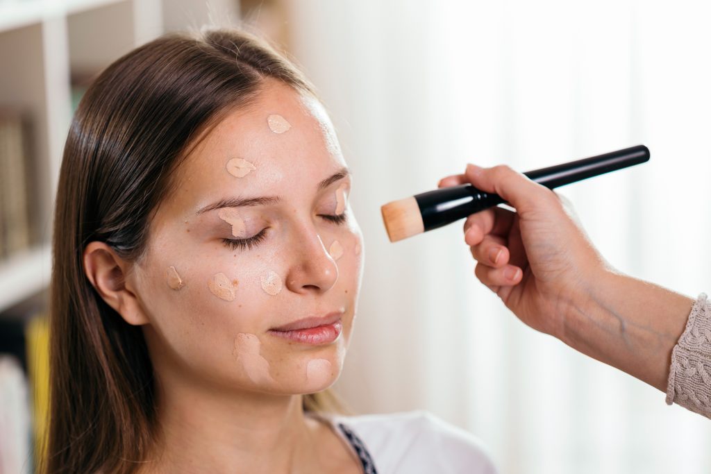 Make up artist applying liquid face powder foundation to a female client's face with a make up brush. Makeup Hacks.