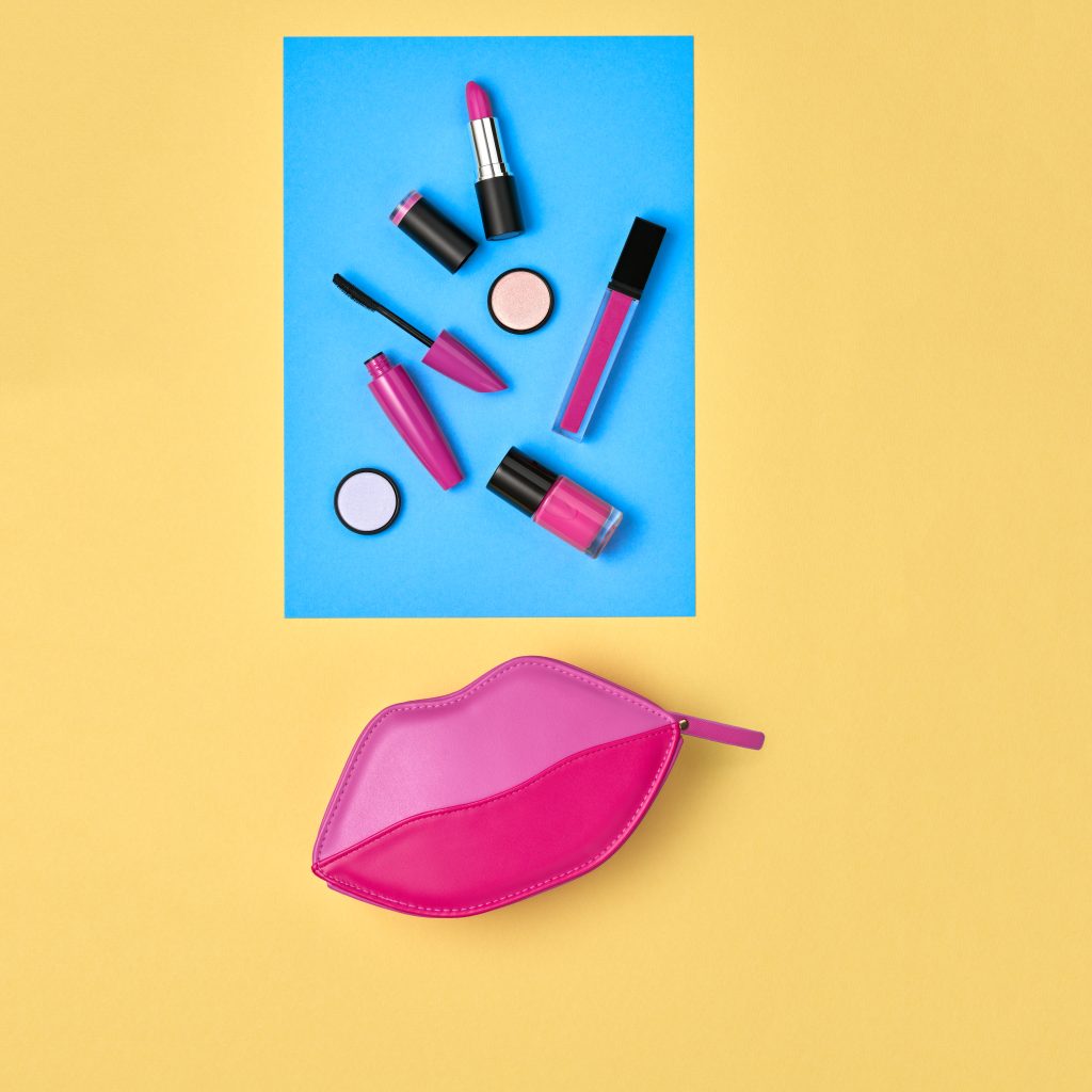 Cosmetic Minimal Makeup Set. Woman Fashion Beauty Accessories. Essentials. Trendy Design Pink Red Clutch Bag. Lipstick Brushes Mascara. Creative Art Concept Style. Flat lay.