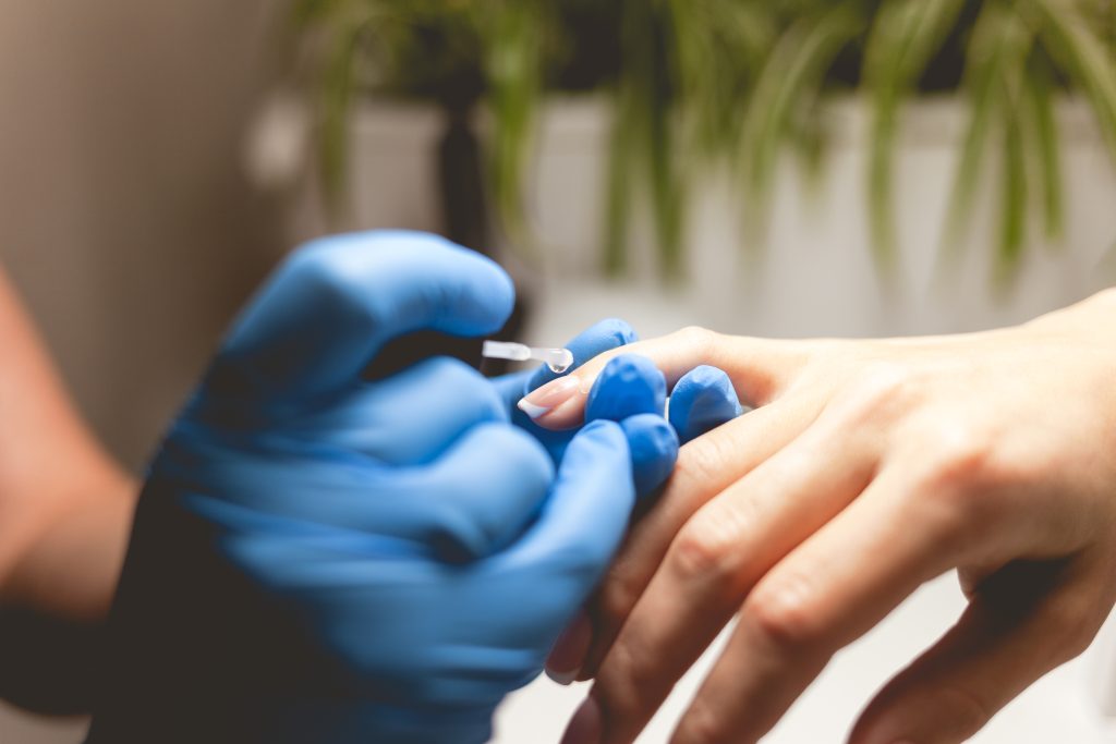 Manicurist varnishes the client's nails, making french style. Manicure process close up