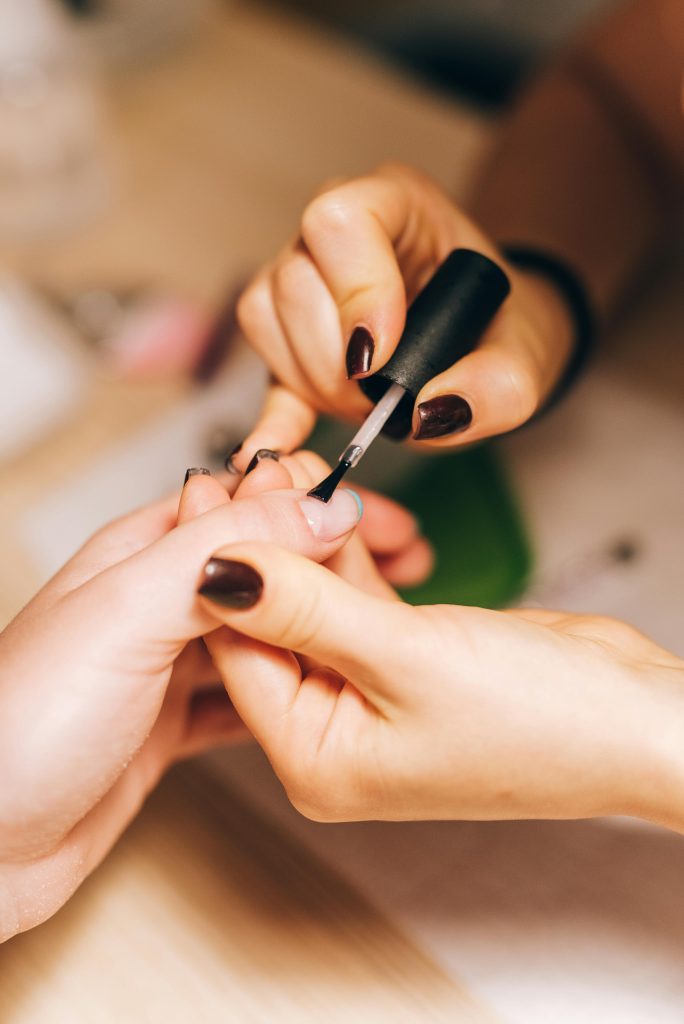 nail adhesive. nail glue. A faceless woman apply nail glue to nails.