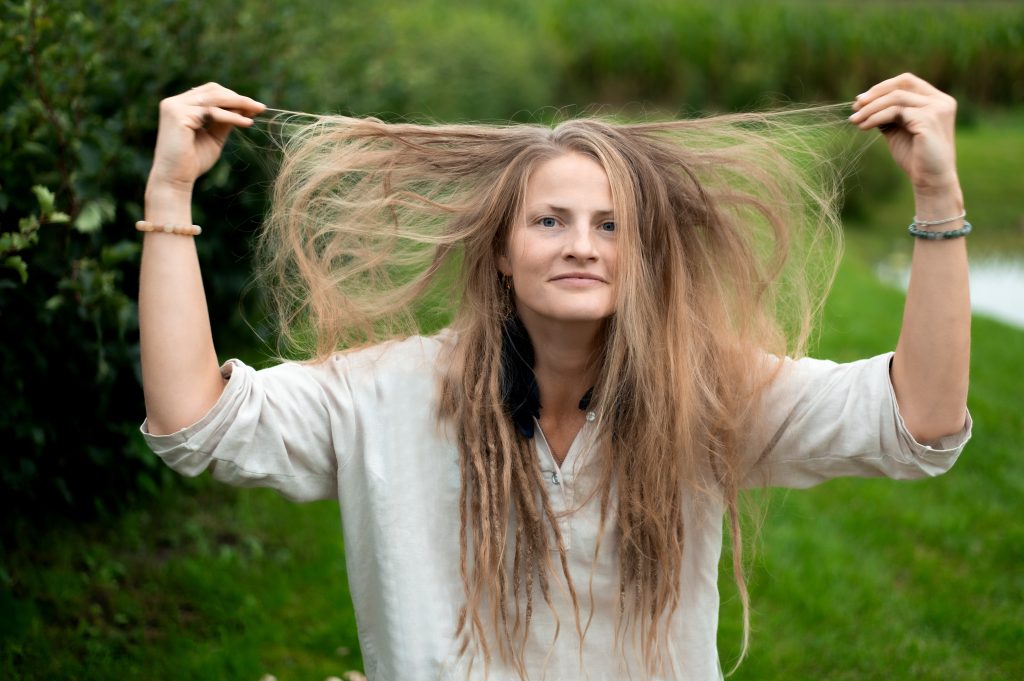 Portrait of young natural woman on green nature background. Shielding Hair from Environmental Damage