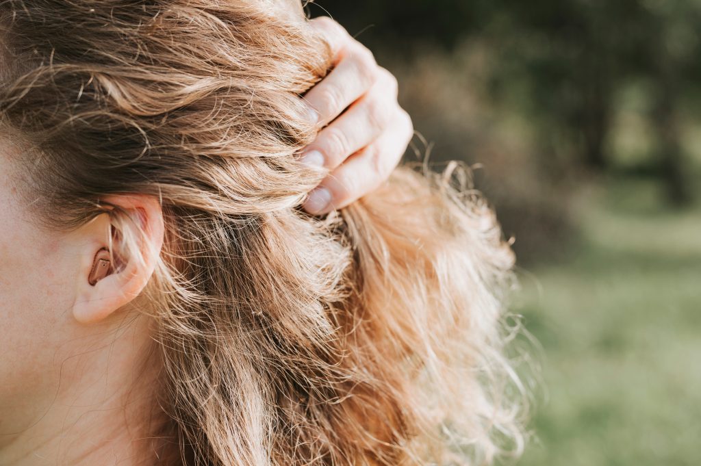 small intra channel hearing aid in the ear of a woman. Avoiding Common Hair Color Mistakes