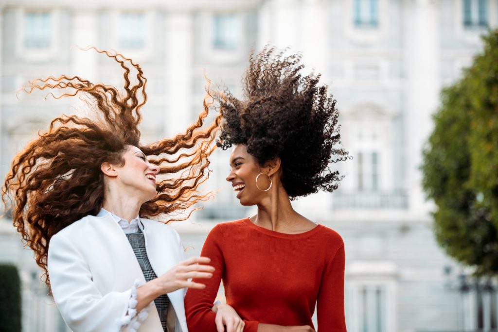 Two cheerful young women walking in the streets of Madrid on winter