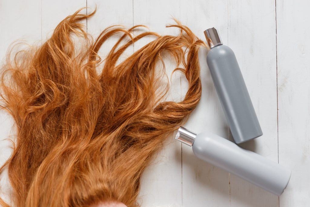 Two shampoo bottles for hair ginger bright color top view, copy space. Beautiful hair care concept 
