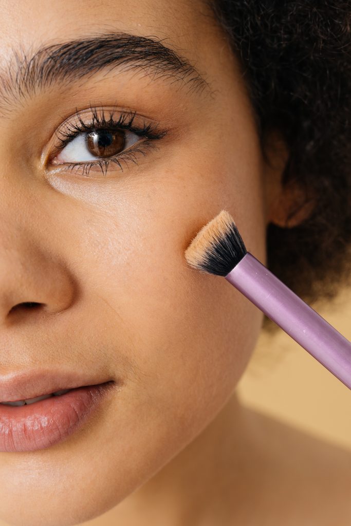 Beauty portrait of beautiful black woman - Pretty african young woman posing in studio, concepts about beauty, cosmetology and diversity. makeup brushes. makeup tools. Concealer Brush