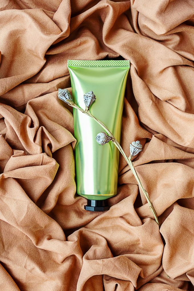 Cosmetic tube on textile background. Skin care beauty product layout.
