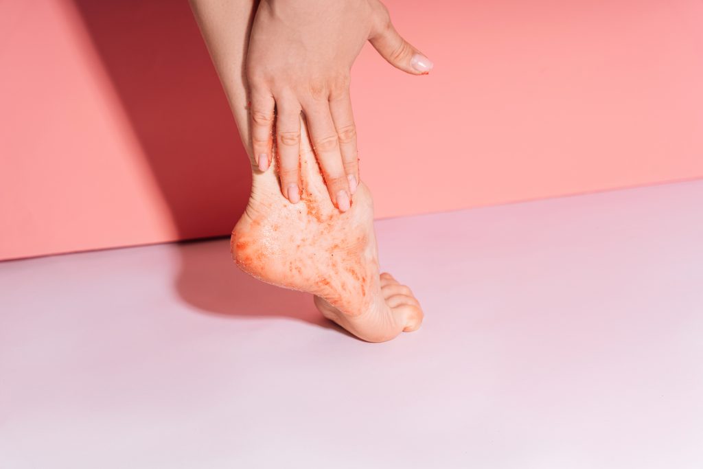 Lady cleanses the skin of her feet with a scrub.