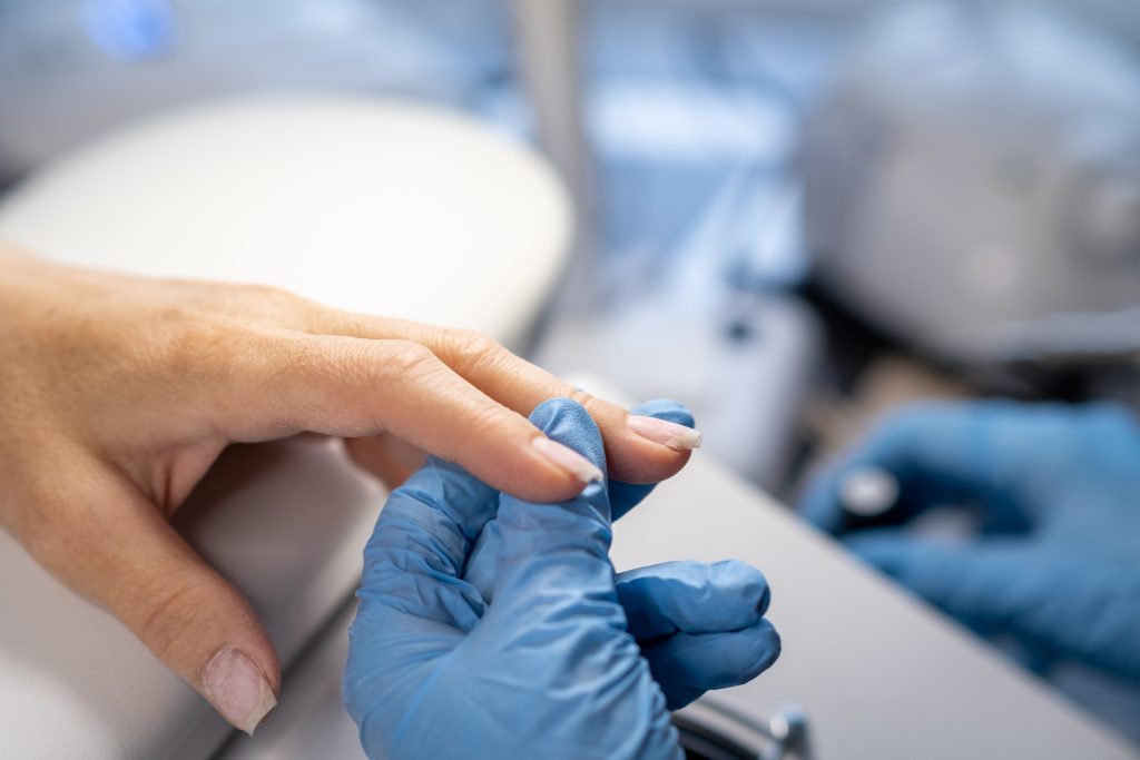 Nail care procedure in a beauty salon. Female hands and tools for manicure, process of performing manicure in beauty salon. Concept spa body care. Gloved hands of a skilled manicurist cutting cuticles. Meet Polygel Nails.