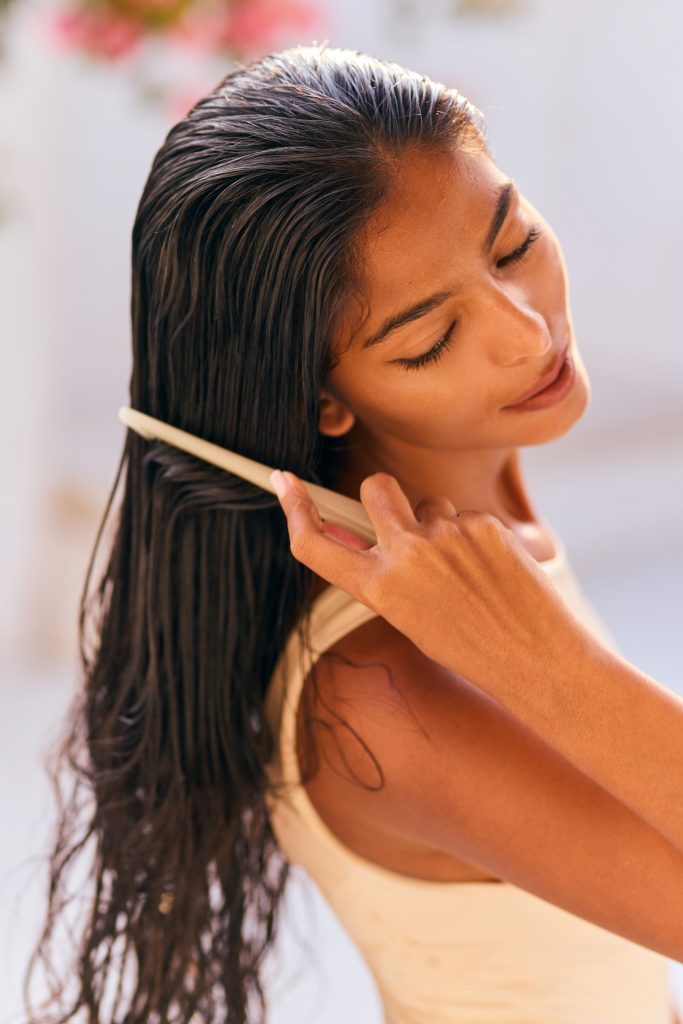 How to Fix Greasy Hair Without Washing It (Instant Results!). Woman Brushing Long Hair Gently, Radiating Relaxation And Beauty. The Soft Natural Light Enhances Her Serene Expression, Capturing A Moment Of Personal Care And Tranquility.