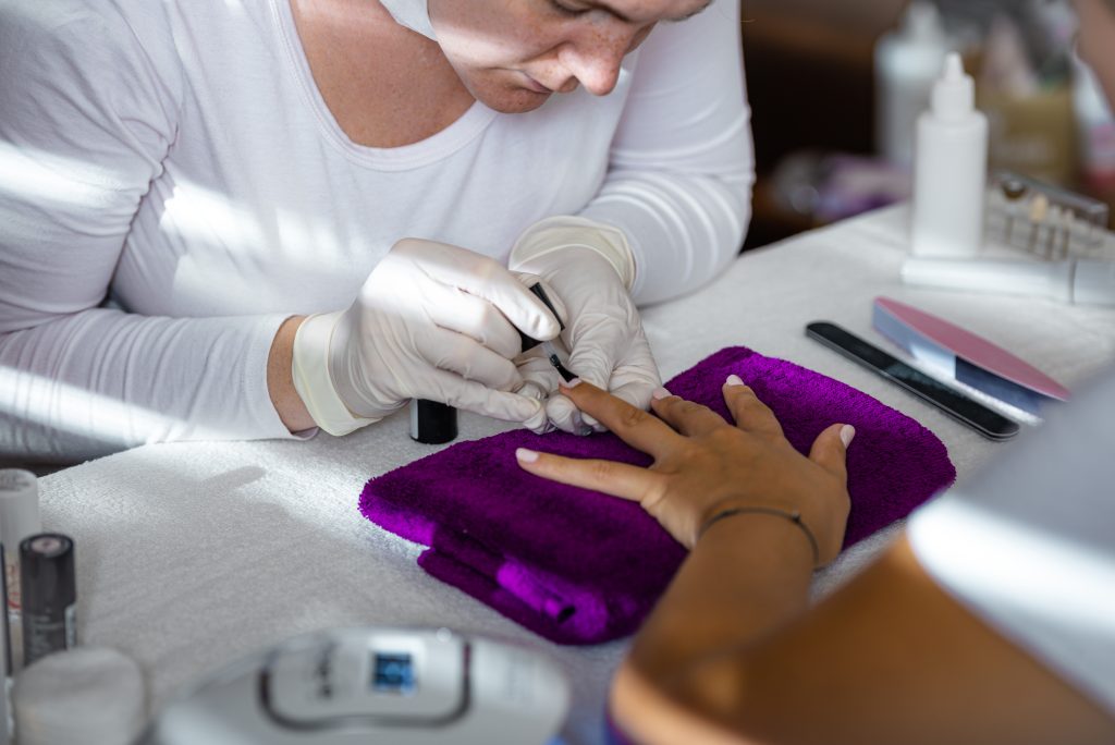 Polygel and Acrylic Extensions | The Hottest Nail Trend Right Now. Woman hands in a beauty salon getting nails polished by a beautician.