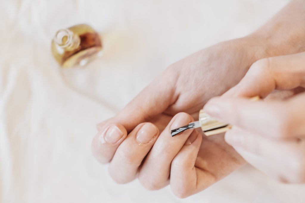 female hands applying cuticle oil. hands and nail care and wellness. beauty treatment at home. self care.