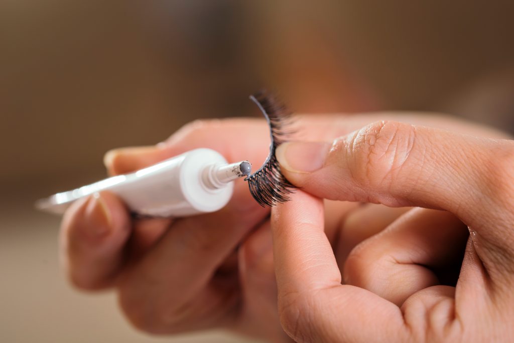 Best Lash Glue. Lash Glue Top Picks. Detail of make up artist's hands adding glue on artificial eyelashes while doing a client's make up 