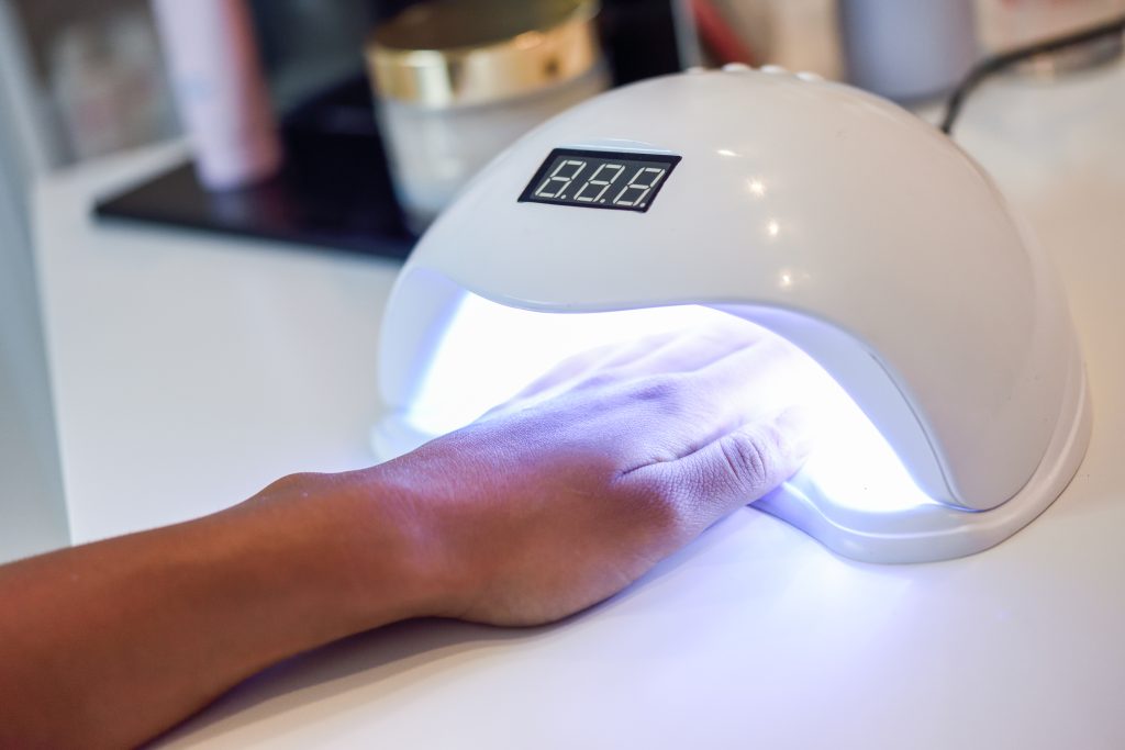 Manicured nails in UV lamp. Small nail art and manicure business. Hands of woman in a wellnes salon. UV Nail Lamps. home manicure. nail polish. 