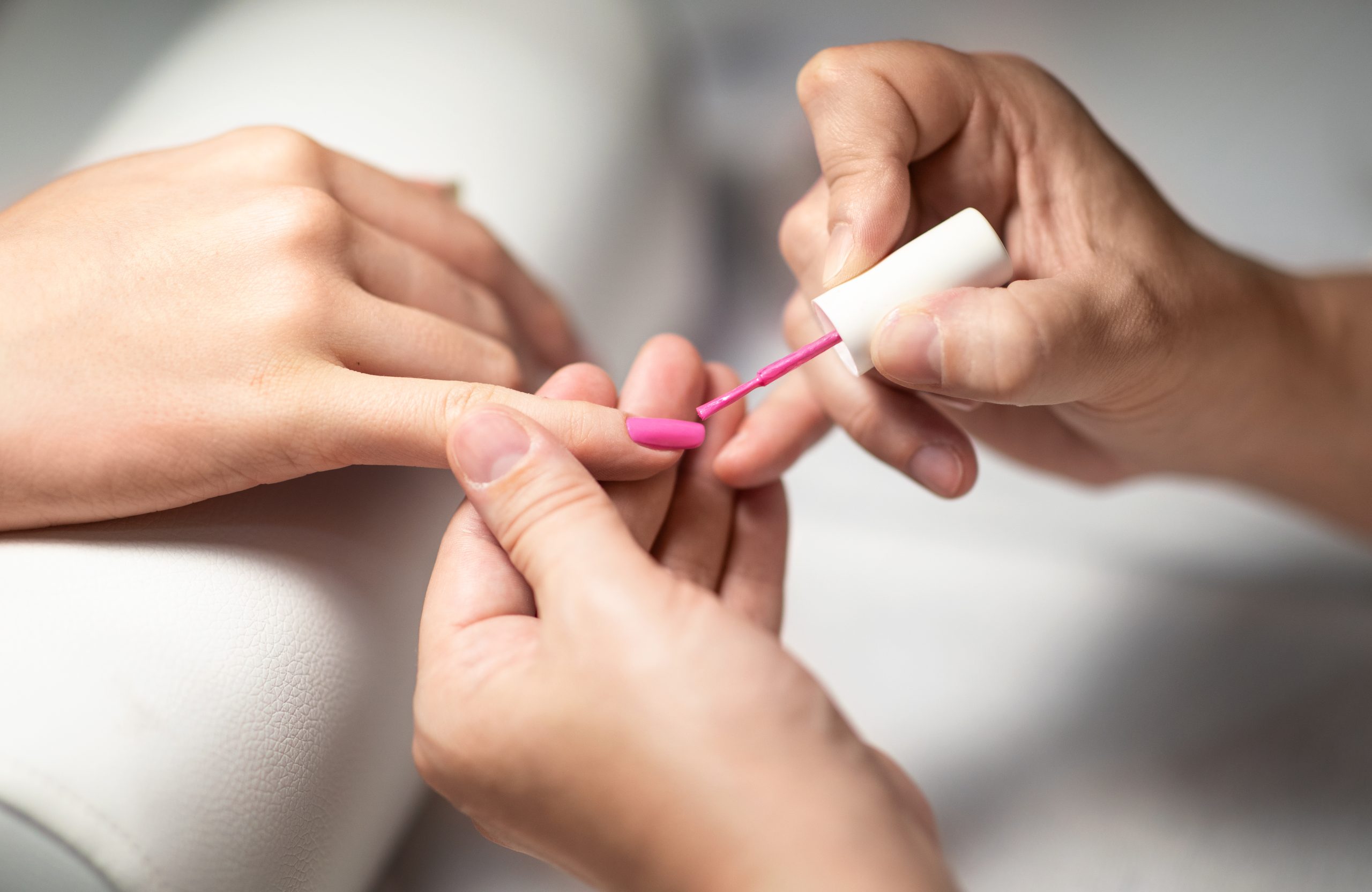 Manicurist Woman Applying Acrylic Pink Gel Polish On Client's Fingernails, Closeup Of Hands. Unrecognizable Lady Doing Professional Manicure At Modern Nail Beauty Studio. Cropped, Selective Focus. nail polish. top nail polish. regular polishes. nail polishes. manicure. home nail care. nail treatment. regular polishes.