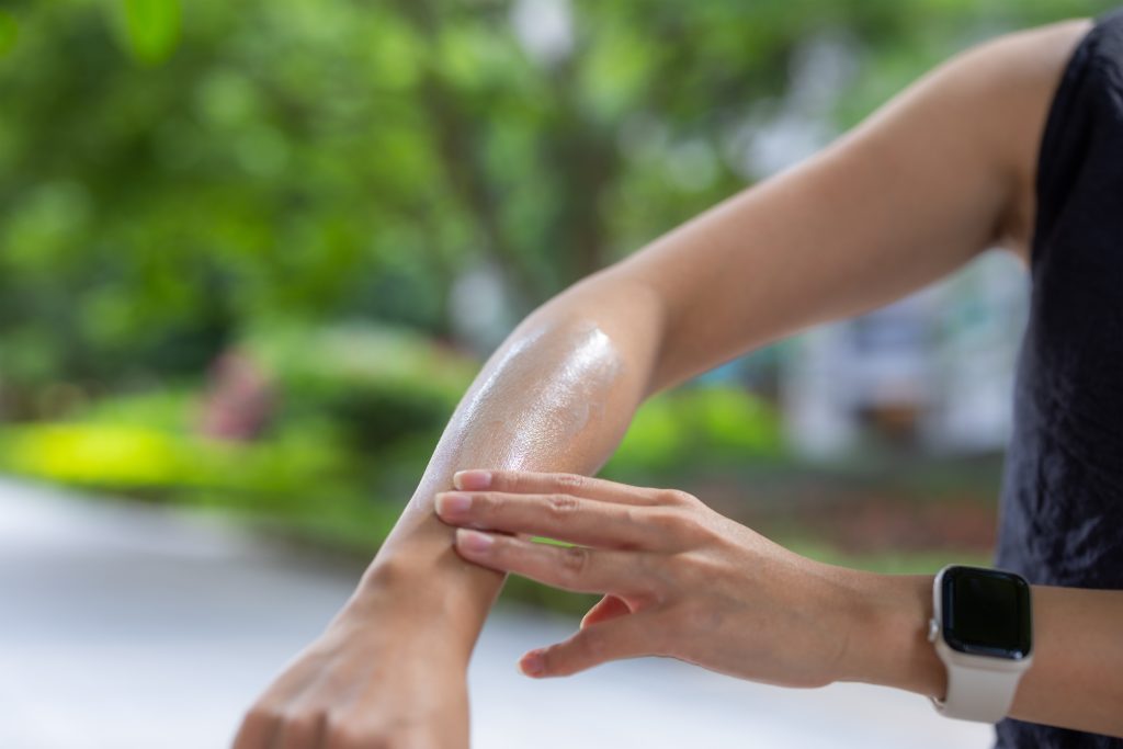 Woman apply sunblock on hand at outdoor. The Best After-Wax Lotions to Soothe and Refresh Your Skin.