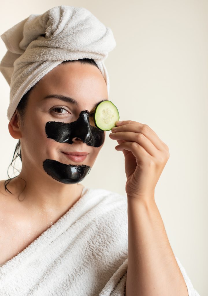 Woman removing blackheads and dark circles with cucumber at home - Home made beauty Spa. Black Facial Masks.
