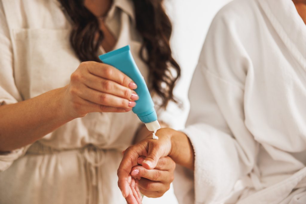 Beautician presenting beauty product to her young female client before spa treatment in a beauty salon. Best Hand Creams for Dry Hands and Cuticles.