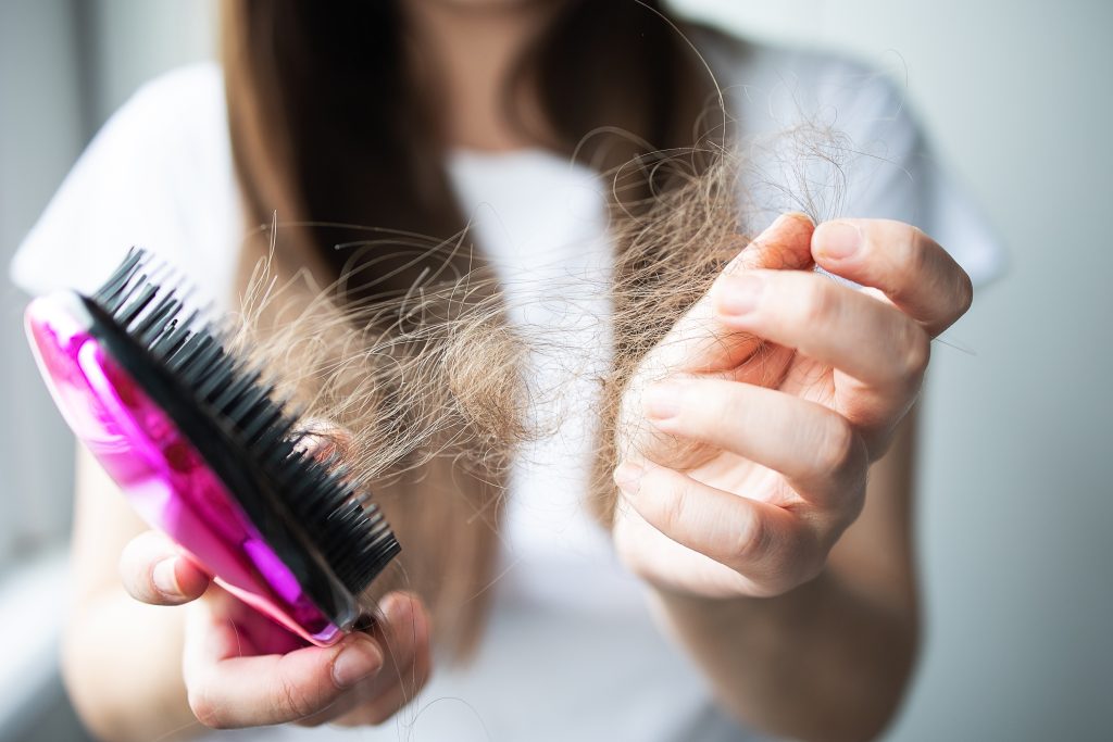 Hair Loss Causes. close up focus on the hands of a comb with fallen hair.