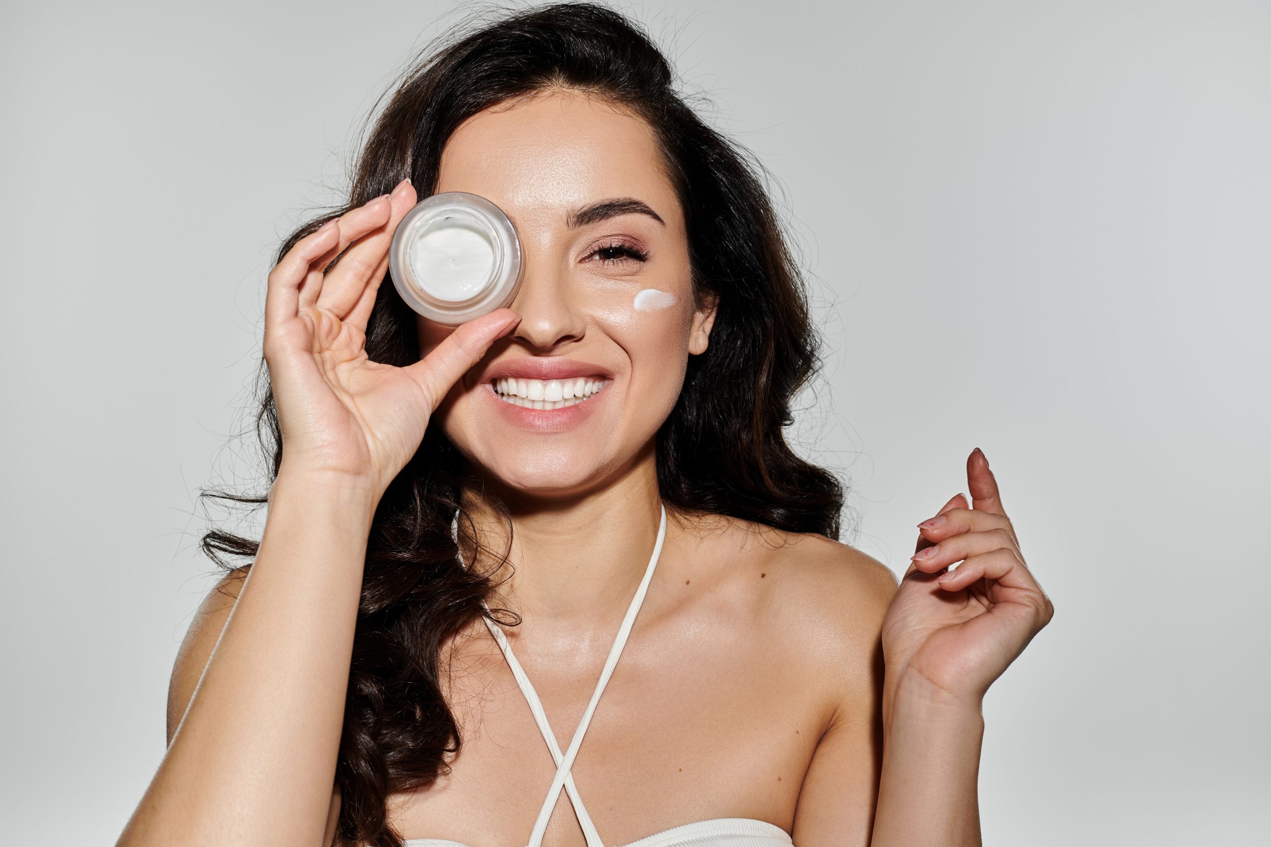 Under Eye Cream. A beautiful young woman demonstrates her skincare routine with joy.