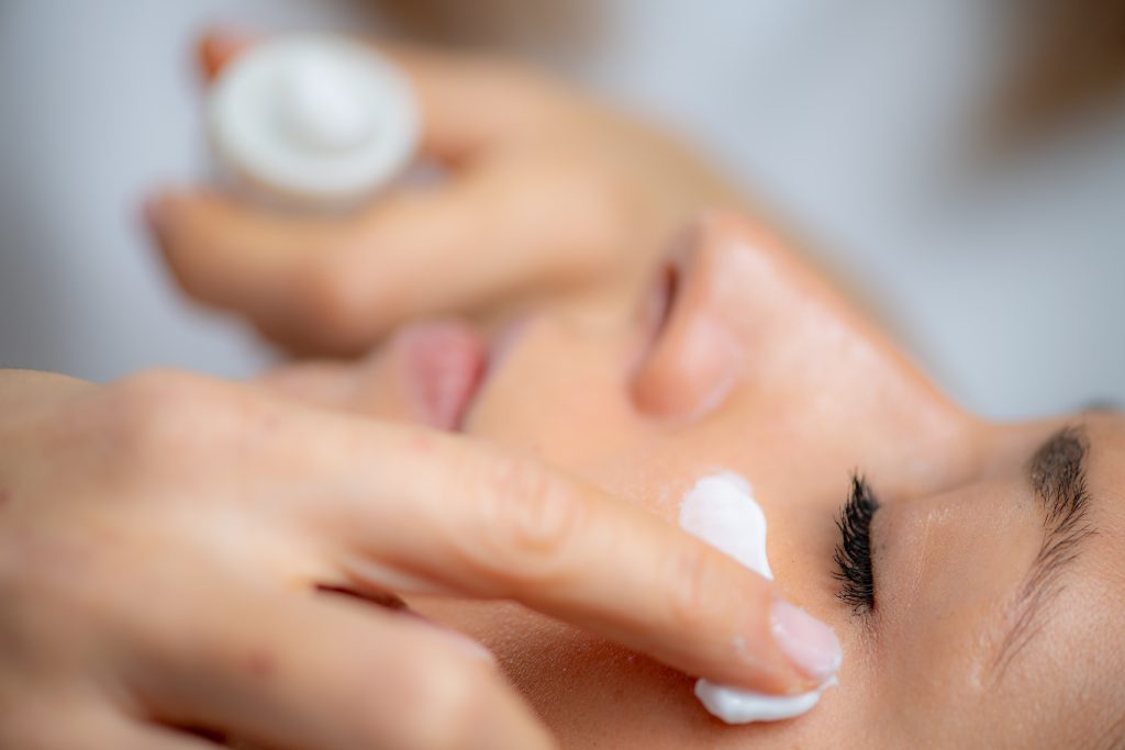 Under Eye Cream. Cosmetician delicately applies cream on woman's face, known for its moisturizing and rejuvenating properties.