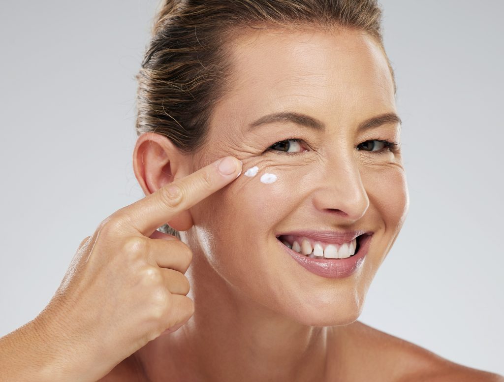 Mature model, skincare and cream on face for beauty, health and happiness with studio background. W.