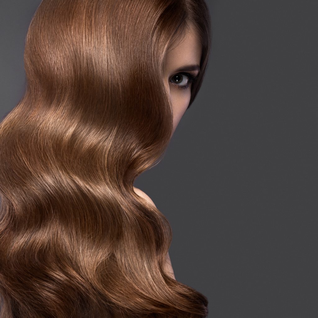 Hair Gloss Treatments. Beautiful brunette girl with a perfectly curls hair and classic make-up. Beauty face. Picture taken in the studio.