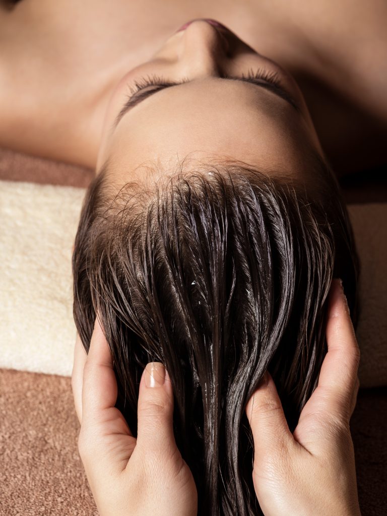 Cosmetologist massaging hair on the head of the woman. Spa treatments. Beauty treatment. Spa salon.