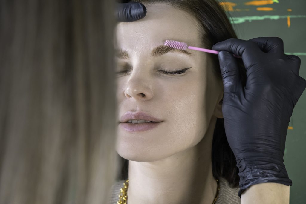 eyebrow painting styling, correction, coloring, and lamination procedure in a beauty salon, eyebrow care treatment. Master applying paint with brush