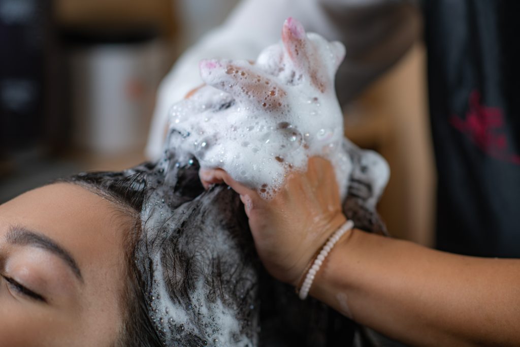 Hairdresser applies shampoo to woman's hair in a salon,  professional hair care expertise