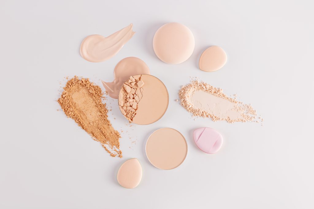 Samples of compact powder and loose powder of different tones, strokes, blocks, sponge on a white background. top view. texture of various powders