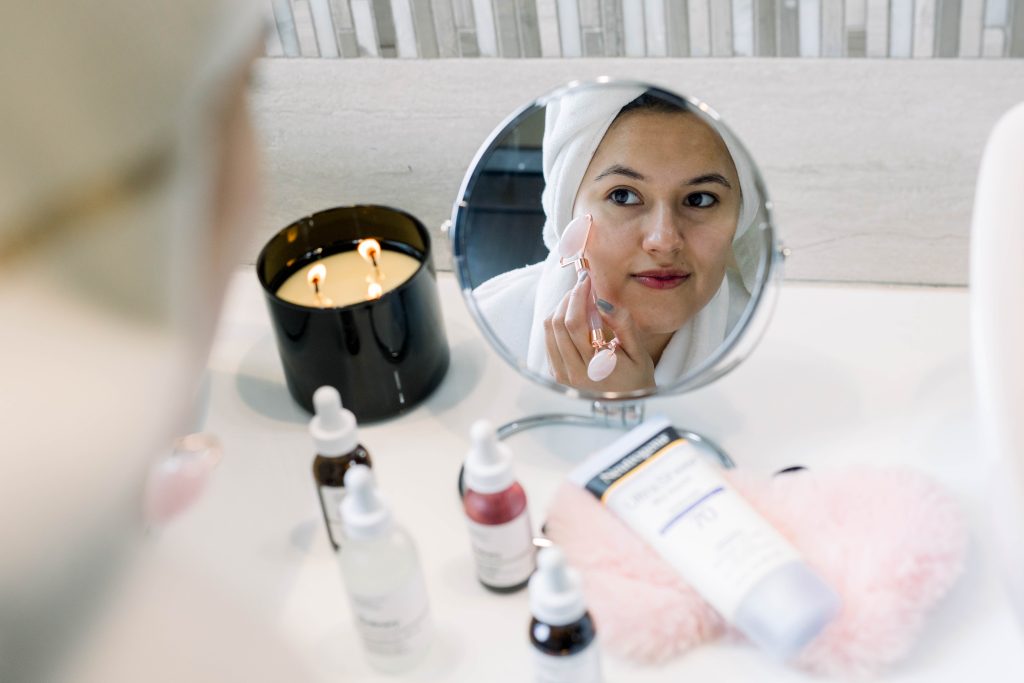 Woman using a rose quartz roller on her skin. Skincare. Night skin care. Evening skincare.