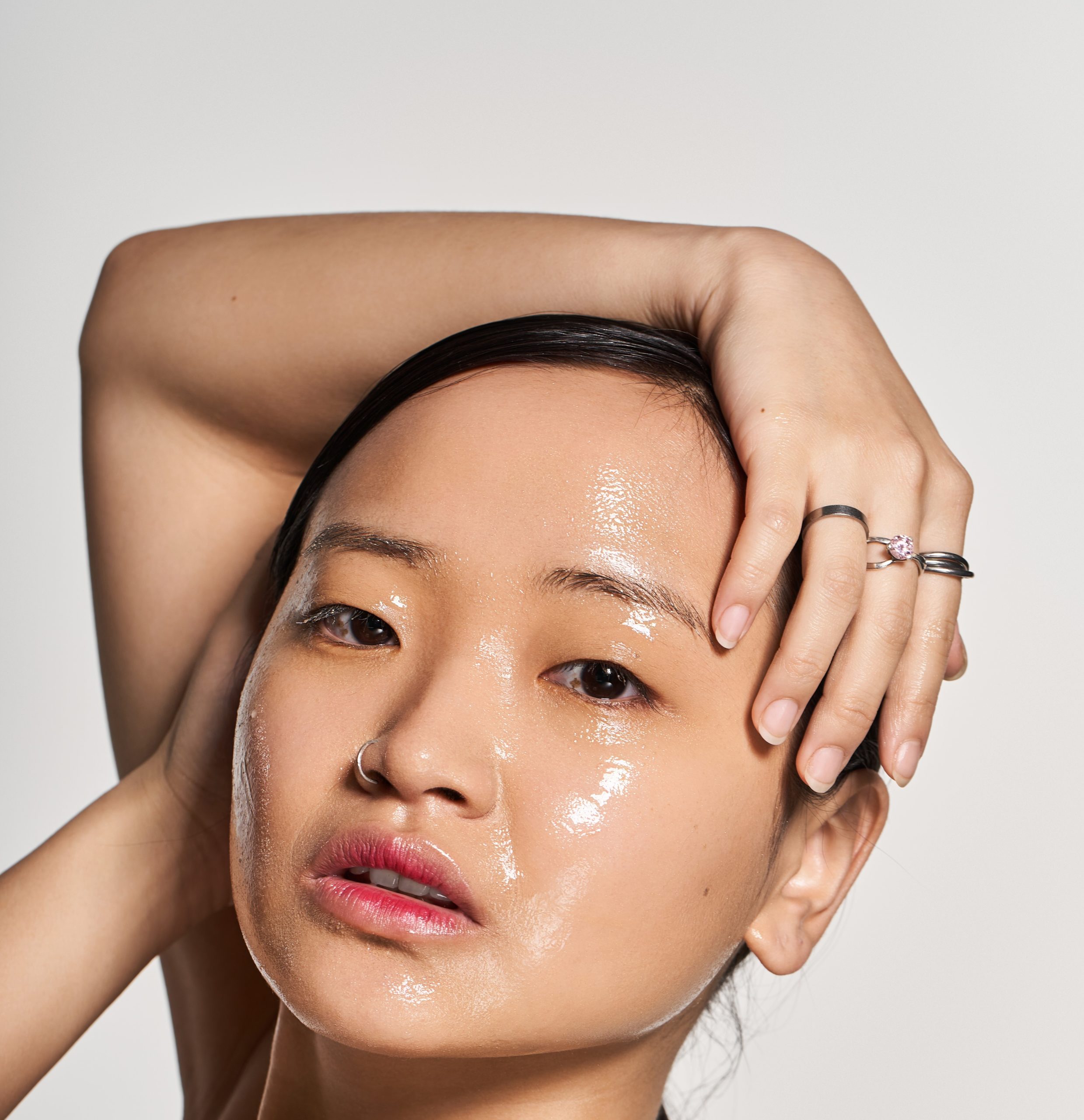 oily skin. Young Asian woman radiates confidence with a glossy complexion in a minimalist setting.