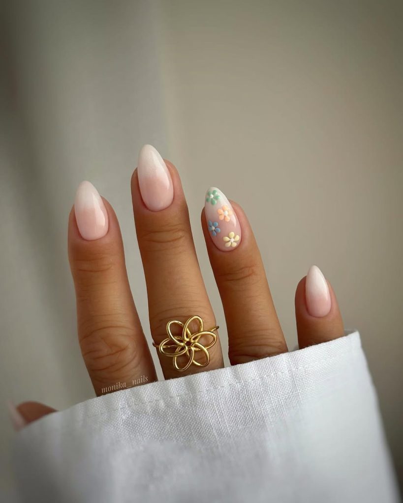 Close-up of Oval nail shapes on a teenager's hand, demonstrating the lengthening effect of the tapered style. The nails have a popular natural ombré or French fade manicure. The accent nail features trendy, colorful 3D floral nail art, a detail often chosen by teenagers looking for creative nail shapes and designs to try at home. This image is ideal for promoting the DIY Oval nail shape tutorial.