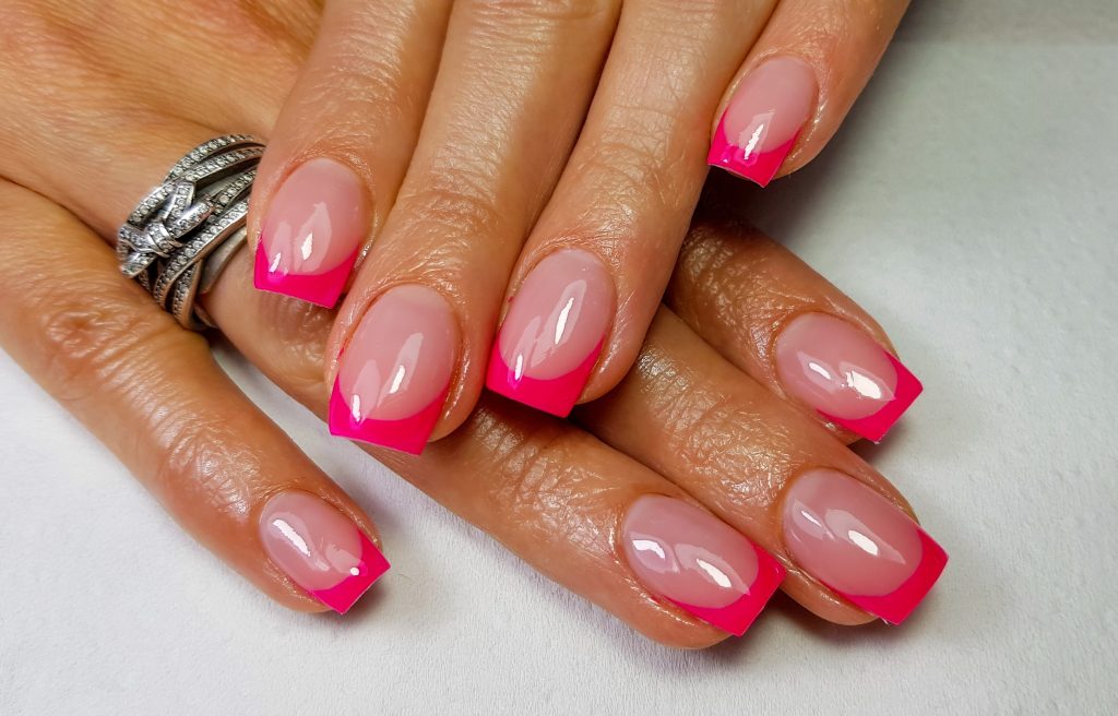 A closeup of a simple pink french manicure on square-shaped nails