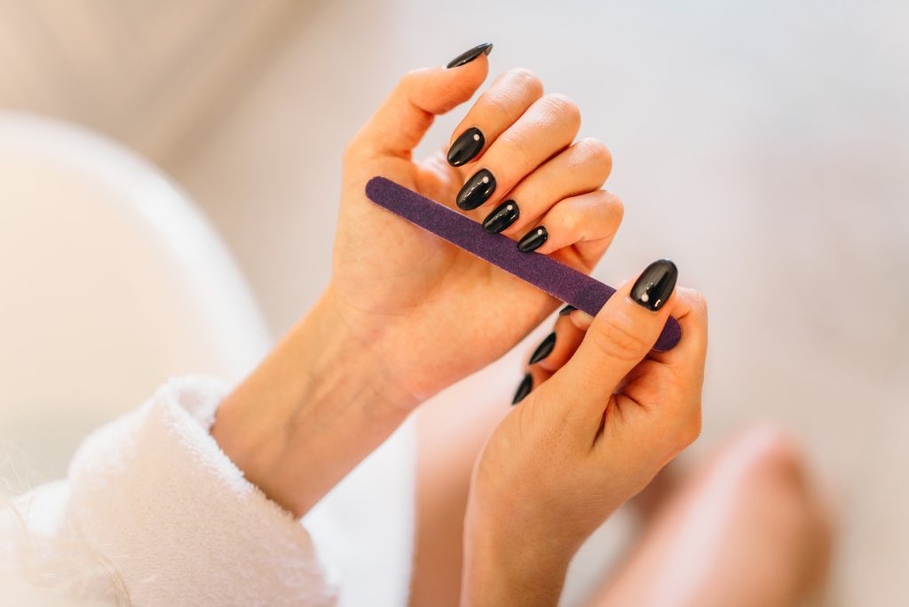 Female person hands with nail file closeup. Manicure procedure, nailcare treatment process