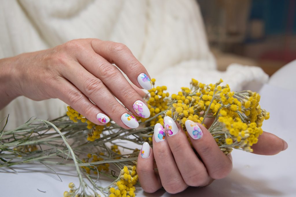 hands with a beautiful multi-colored manicure hold a bouquet of yellow flowers. High quality photo