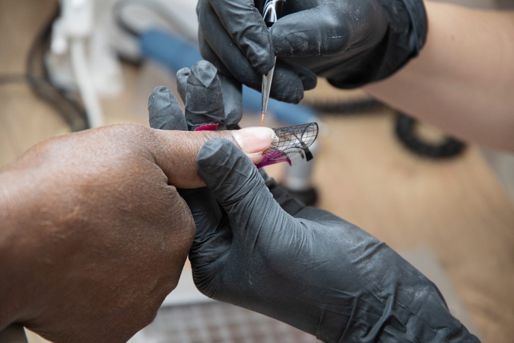 Manicurist doing nail extensions to dark-skinned girls in a beauty salon. High quality photo