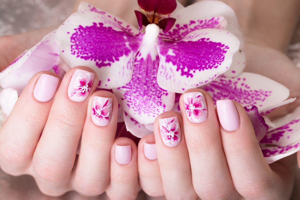 Shot beautiful manicure with flowers on female fingers. Nails design. Close-up. Picture taken in the studio on a white background.
