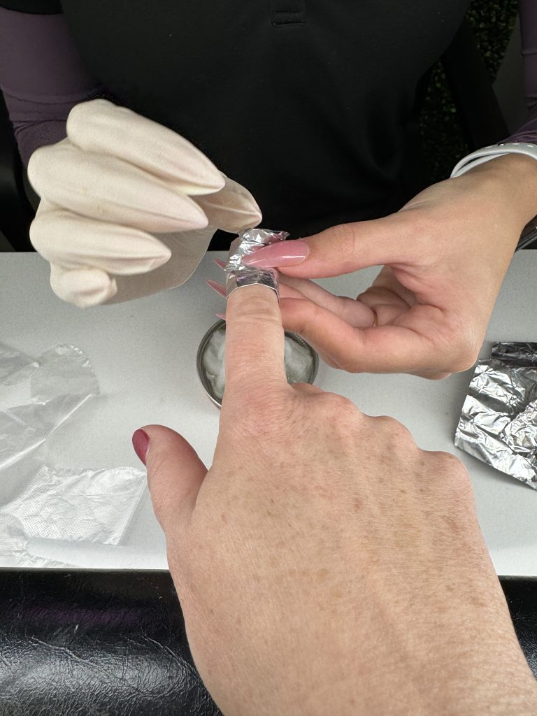 Woman getting polygel nails safely removed at a nail salon.