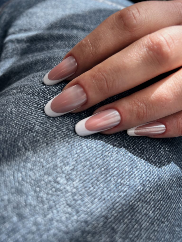 A closeup image of a female hand with professionally painted nails in natural tones