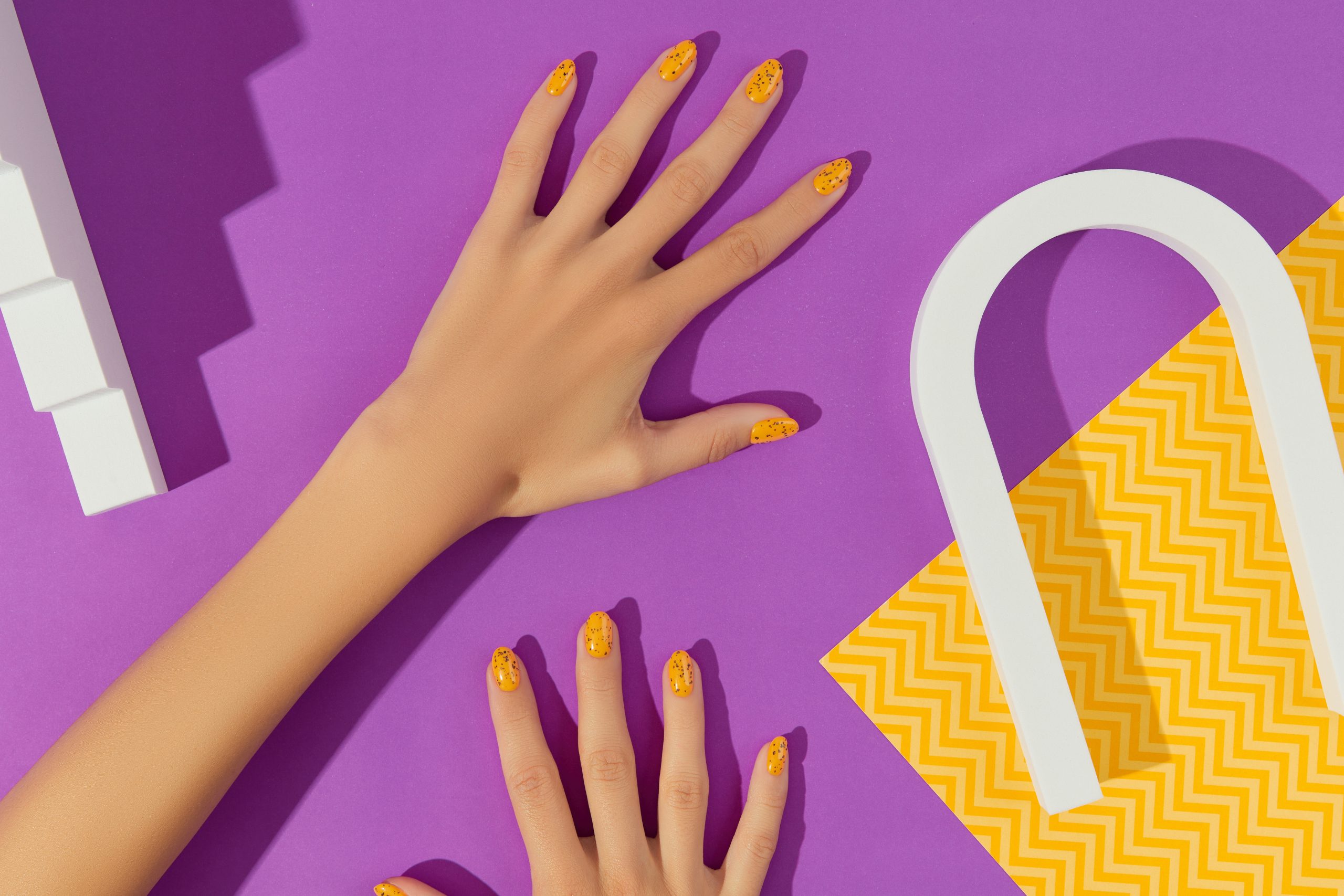Manicured womans with trendy nail design on purple background. Beauty treatment self-care concept