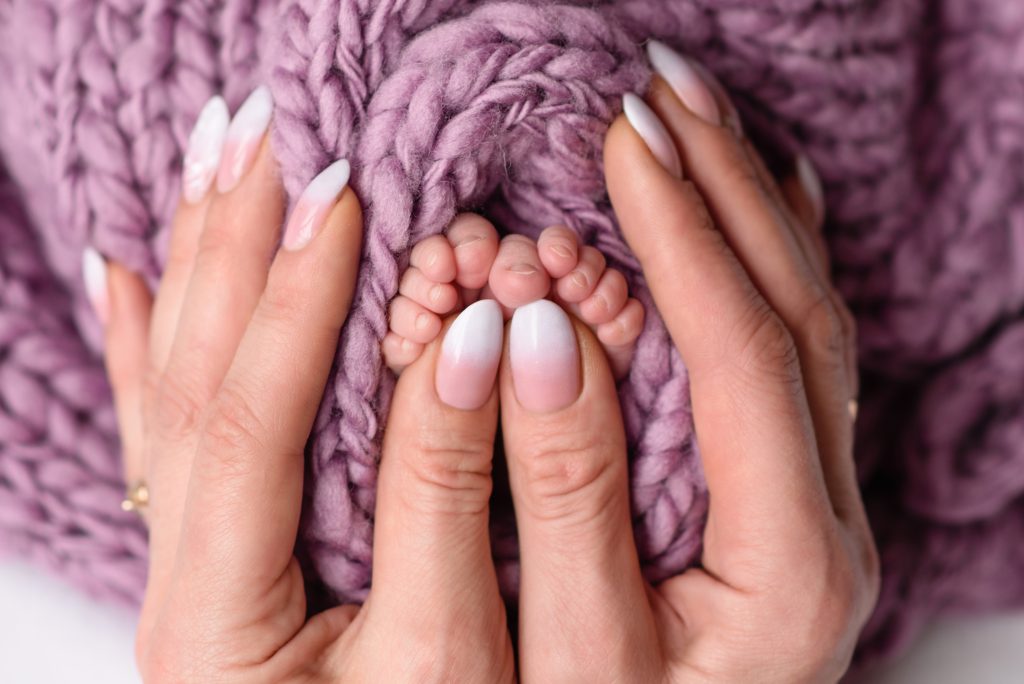 Small beautiful legs of a newborn baby in the first days of life. Baby feet of a newborn. Nail Shapes for Moms