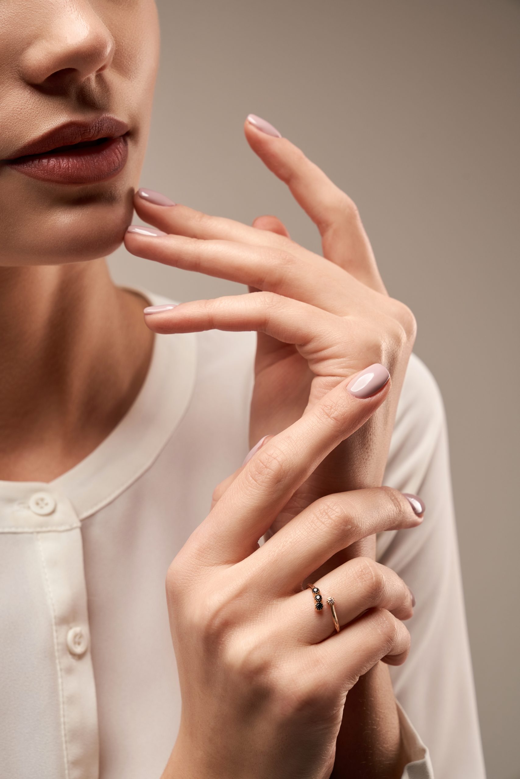 2026 color trends. Close up portrait of incognito female model presenting silver ring with black and white stones. Crop of woman posing in studio, isolated on grey background. Concept of expensive jewelry.
